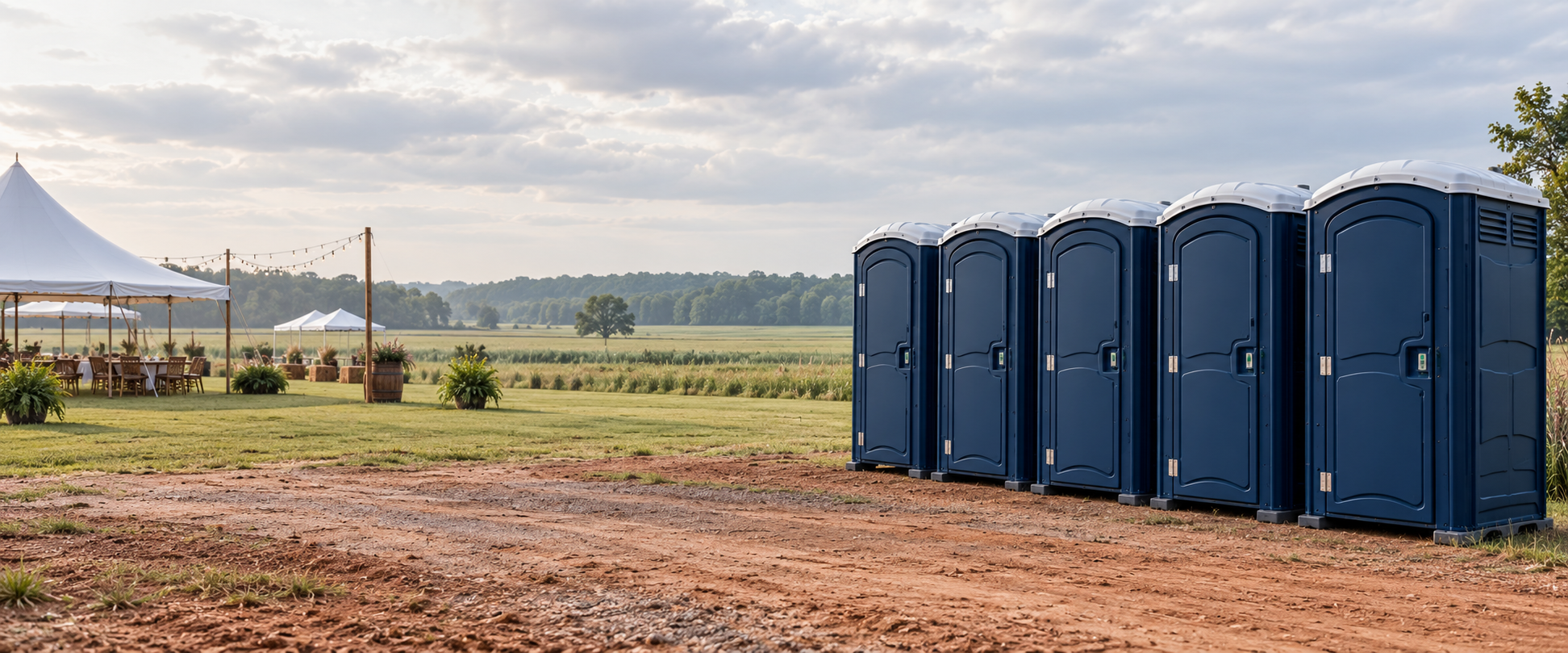 Portable restrooms arranged beside an outdoor event lawn in an Arkansas field